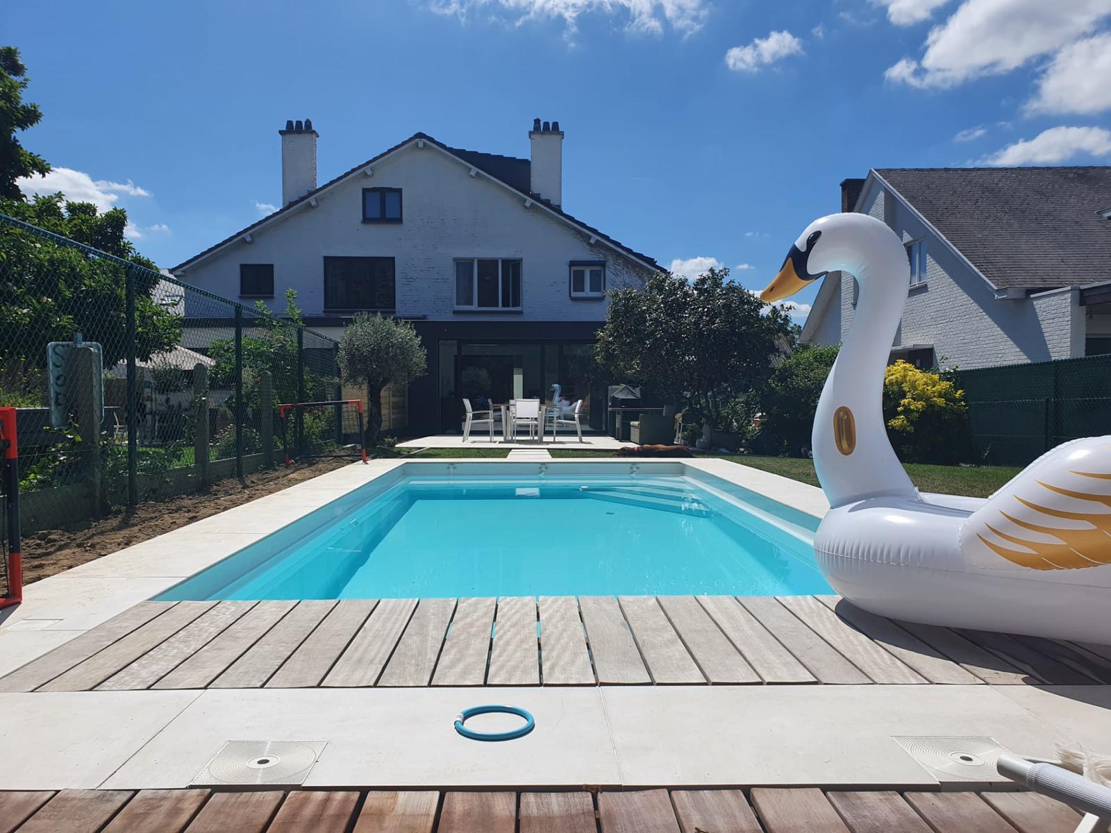 Aanleg van een strak rechthoekig buitenzwembad met lichte boordstenen.